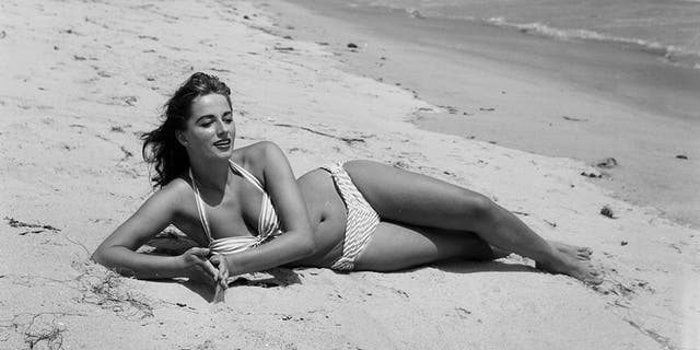 Eine glamouröse Aufnahme von Jackie Collins, wie sie im Bikini am Strand posiert