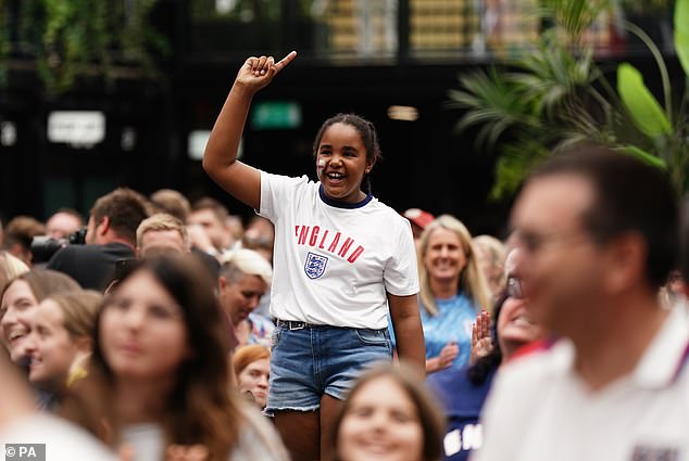 A young England fan smiles as she urges her team on in a screening of the match in London