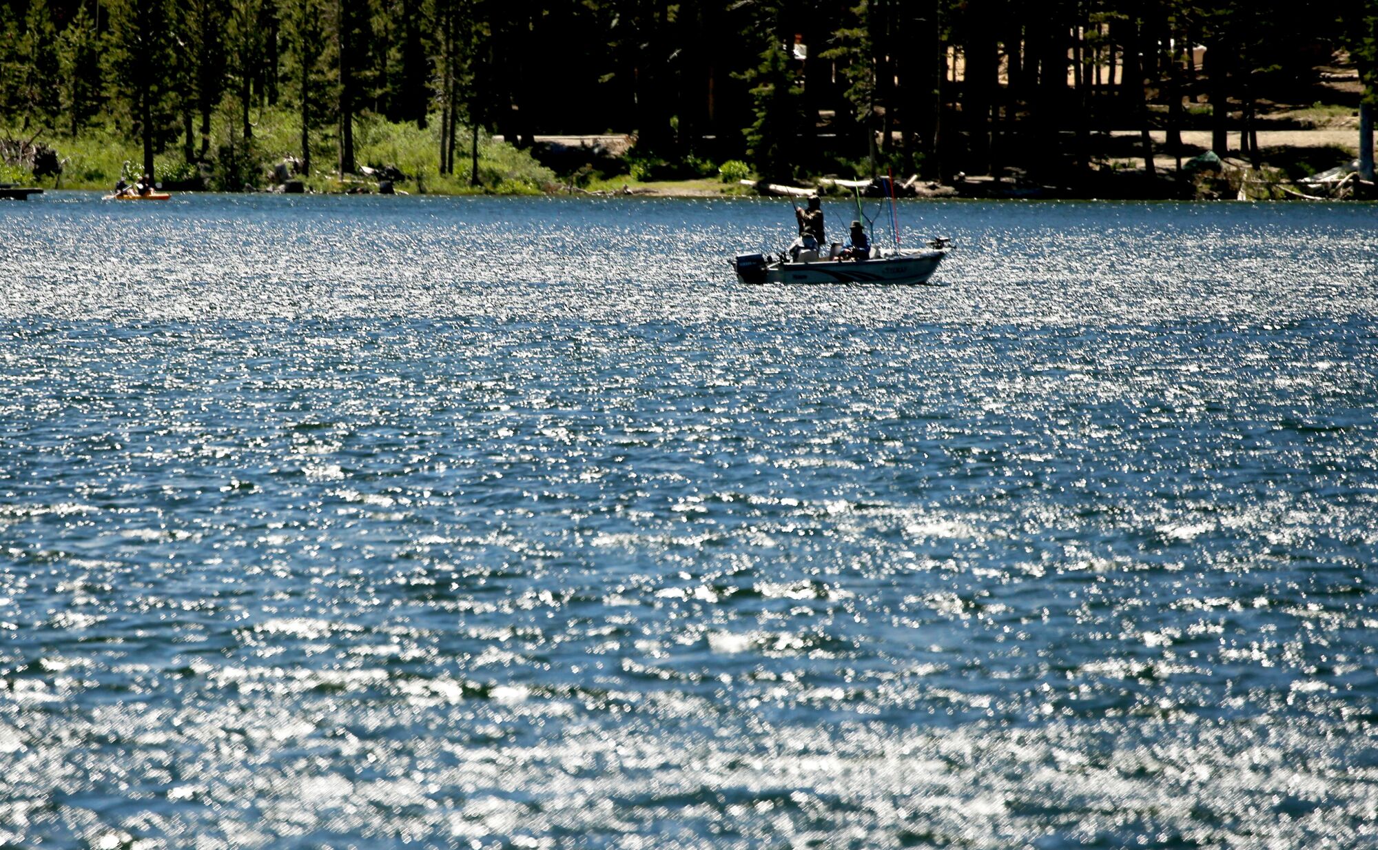 Angler werfen in einem kleinen Motorboot Leinen in einen strahlend blauen See.