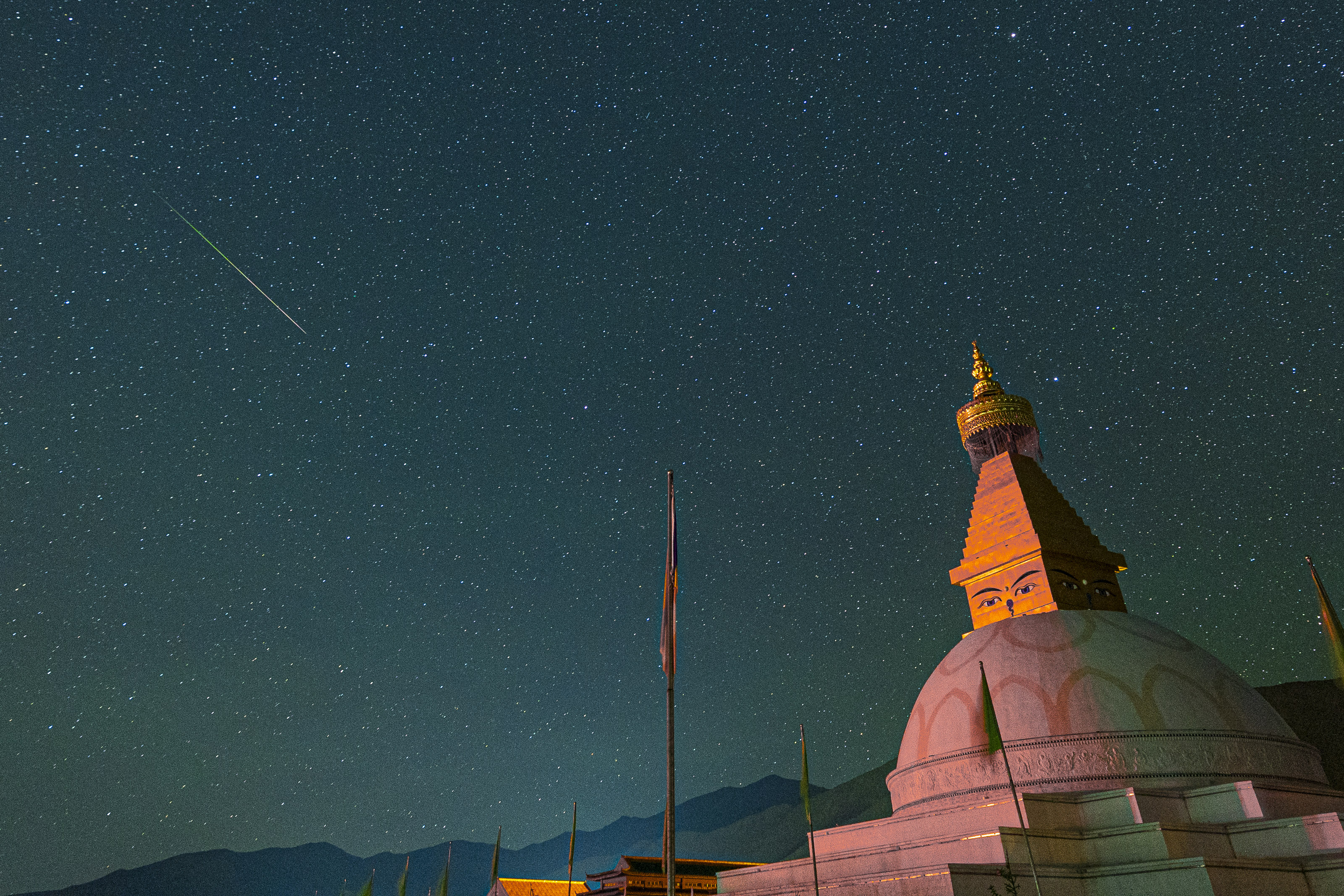 Perseiden-Meteor schießt über einem großen Kuppelgebäude über den Himmel.