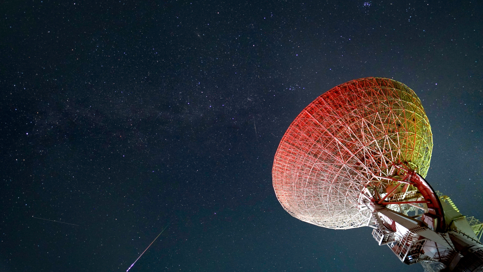 Helle Perseiden-Meteore streifen über den sternenübersäten Himmel mit einer großen Teleskopschüssel auf der rechten Seite des Bildes.