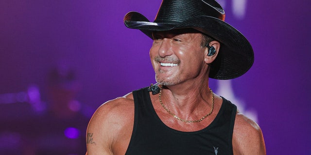 Tim McGraw tritt live in einem schwarzen Tanktop und einem passenden Cowboyhut auf