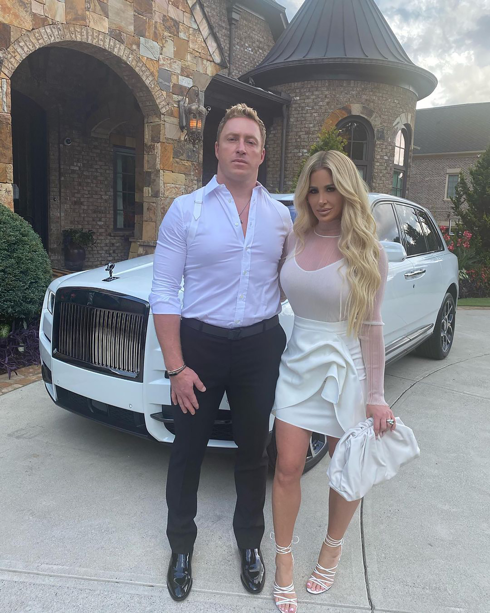 Kim Zolciak und Kroy Biermann posieren vor einem Auto und ihrer Villa.