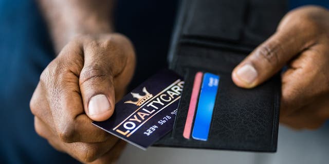 Foto eines Mannes, der seine Kundenkarte aus seinem Portemonnaie zieht.