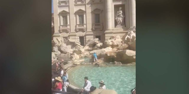 Tourist füllt Wasserflasche am Trevi-Brunnen