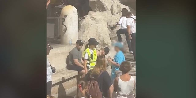Wachmann hält Touristen am Trevi-Brunnen an