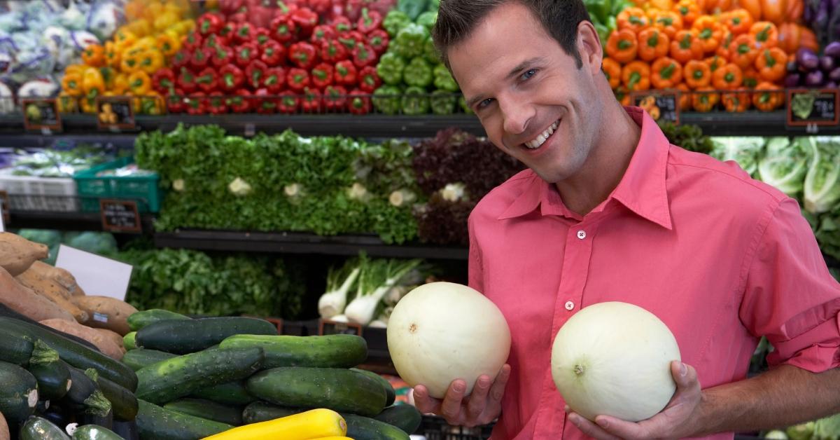 Mann hält Melonen vor die Brust, lächelnd, Porträt, Nahaufnahme – Stockfoto