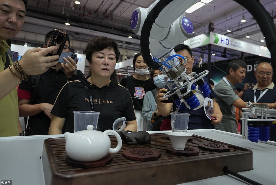 Visitors look at a robotic arm performs a Chinese tea serving during the hotly-anticipated annual event