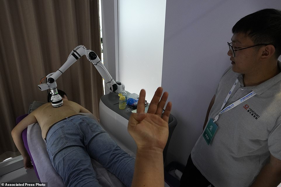 Just a bit higher please!: An exhibitor watches a visitor receiving a massage by a robotic arm
