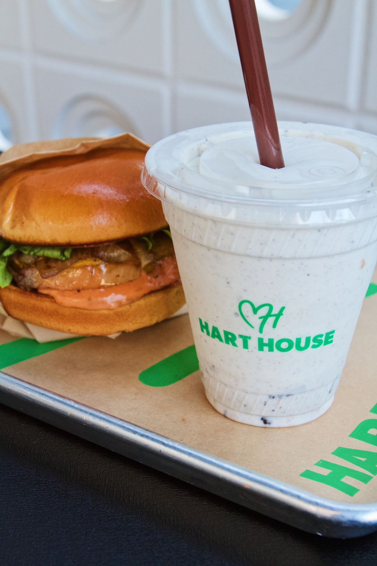 Ein doppelter Cheeseburger und ein Oreo-Shake auf einem silbernen Tablett vor einer weißen Wand der veganen Kette Hart House.