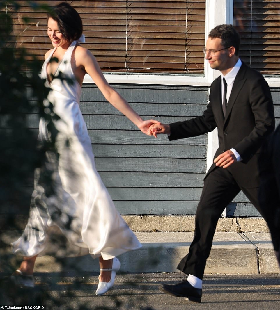 Hand in hand: Jack also went for a classically stylish look, going down the aisle in a black tuxedo and matching tie; he and his bride are pictured outside the reception