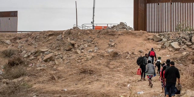 Migranten laufen auf den Grenzmauerspalt zu