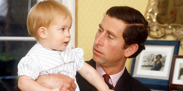 Eine Nahaufnahme von Prinz Charles, der sein Baby Prinz Harry hält