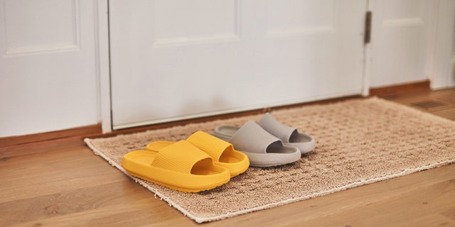 Slip-On-Sandalen liegen auf einer Fußmatte neben einer Eingangstür.