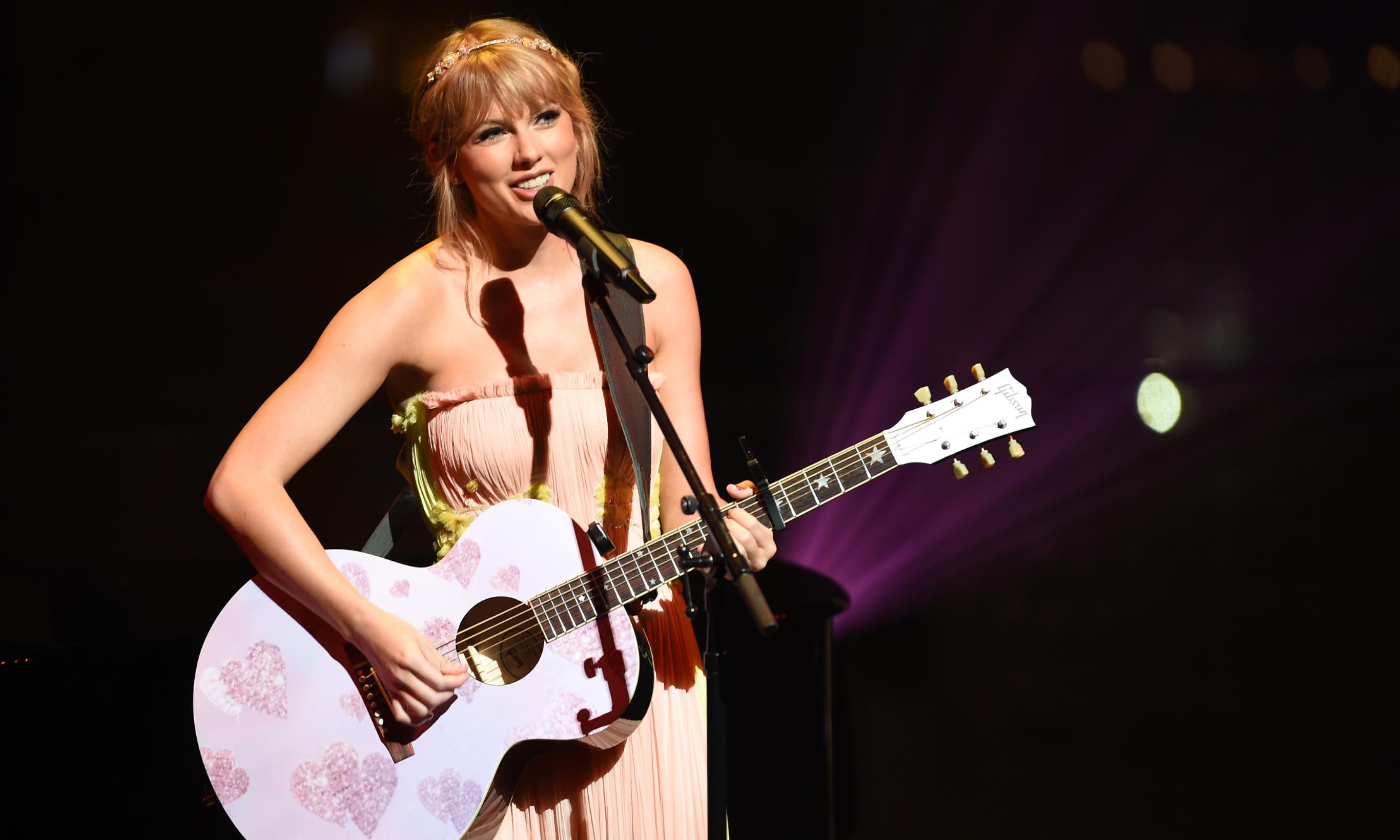 Taylor Swift hält rosa Gitarre