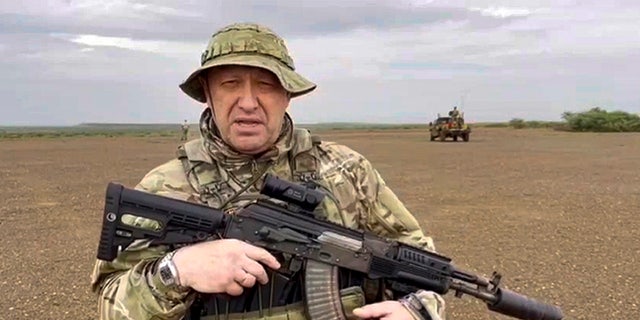 Prigozhin in Militäruniform hält eine Waffe in der Hand