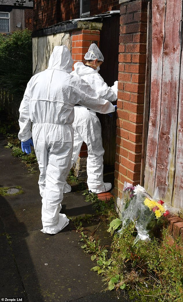 Scenes of crime officers are pictured entering the garden of the property, passing by floral tributes left in honour of Mr Patience
