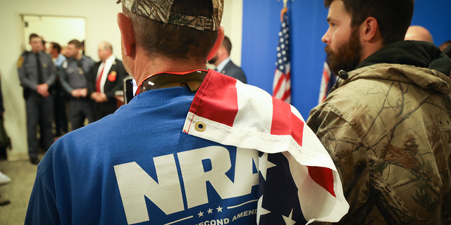 Mann im blauen NRA-Shirt mit US-Flagge auf der Schulter