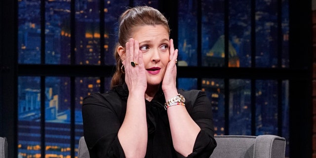 Drew Barrymore in einem schwarzen Kleid hebt verzweifelt die Hände vors Gesicht "Late Night mit Seth Meyers"
