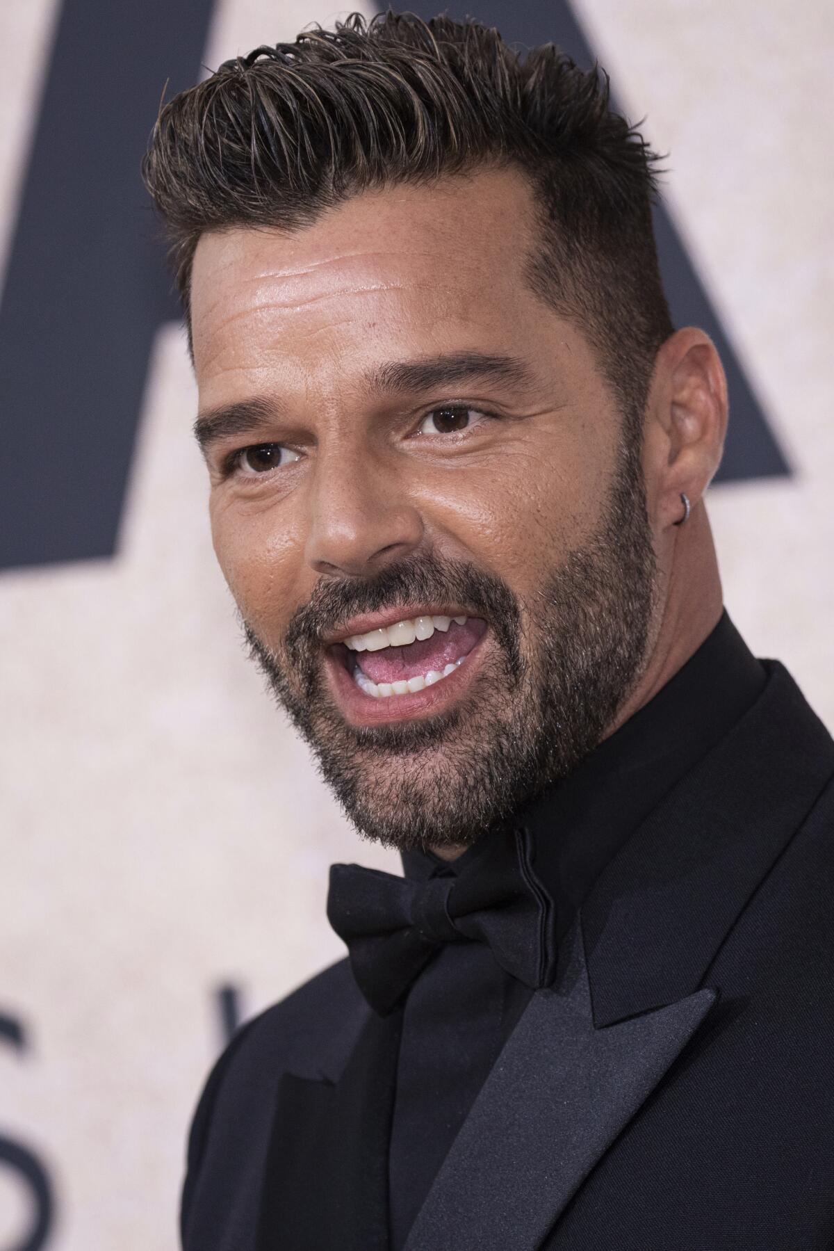 Ricky Martin posiert und lächelt im schwarzen Smoking, Hemd und Fliege