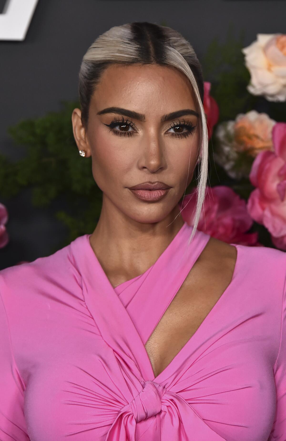 Kim Kardashian posiert in einem pinkfarbenen Top mit gebleichten Strähnen im Haar