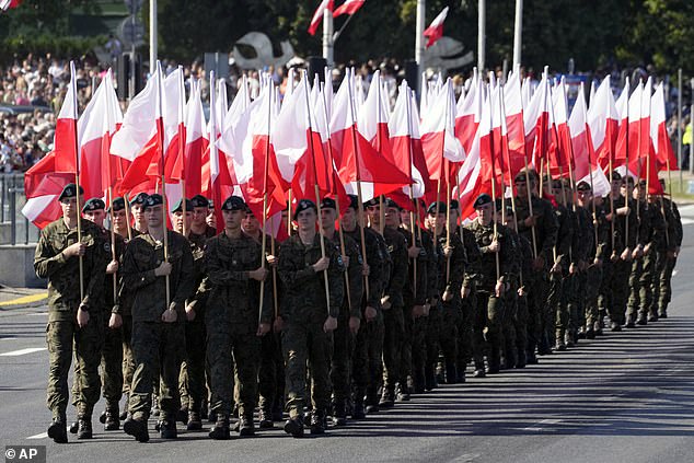 Poland¿s governing PiS Party used the parade to showcase the nation¿s state-of-the-art weaponry alongside 2,000 troops, 200 armed-forces vehicles and 100 aircraft. Pictured: Members of the new voluntary Territorial Defense Troops march with Poland's national flags