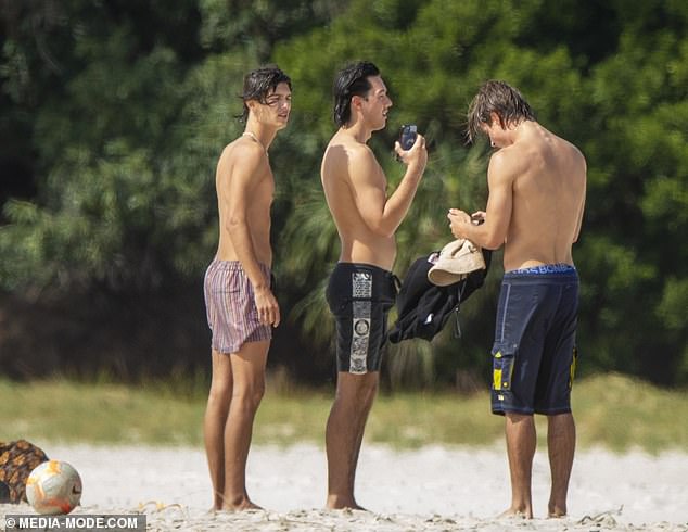 Die Herren ohne Hemd machten Fotos am Strand