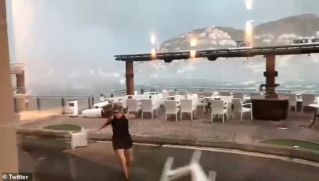 Eine Frau sprintet in Deckung, während Stühle hinter ihr am Sonntag auf Mallorca vom Wind weggeweht werden