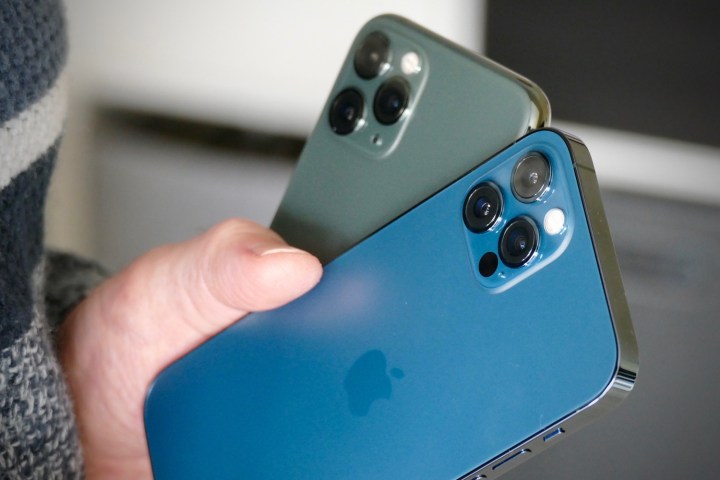 iPhone 11 Pro in Mitternachtsgrün mit einem iPhone 12 Pro in Pazifikblau in der Hand, das Kameramodule vorführt.
