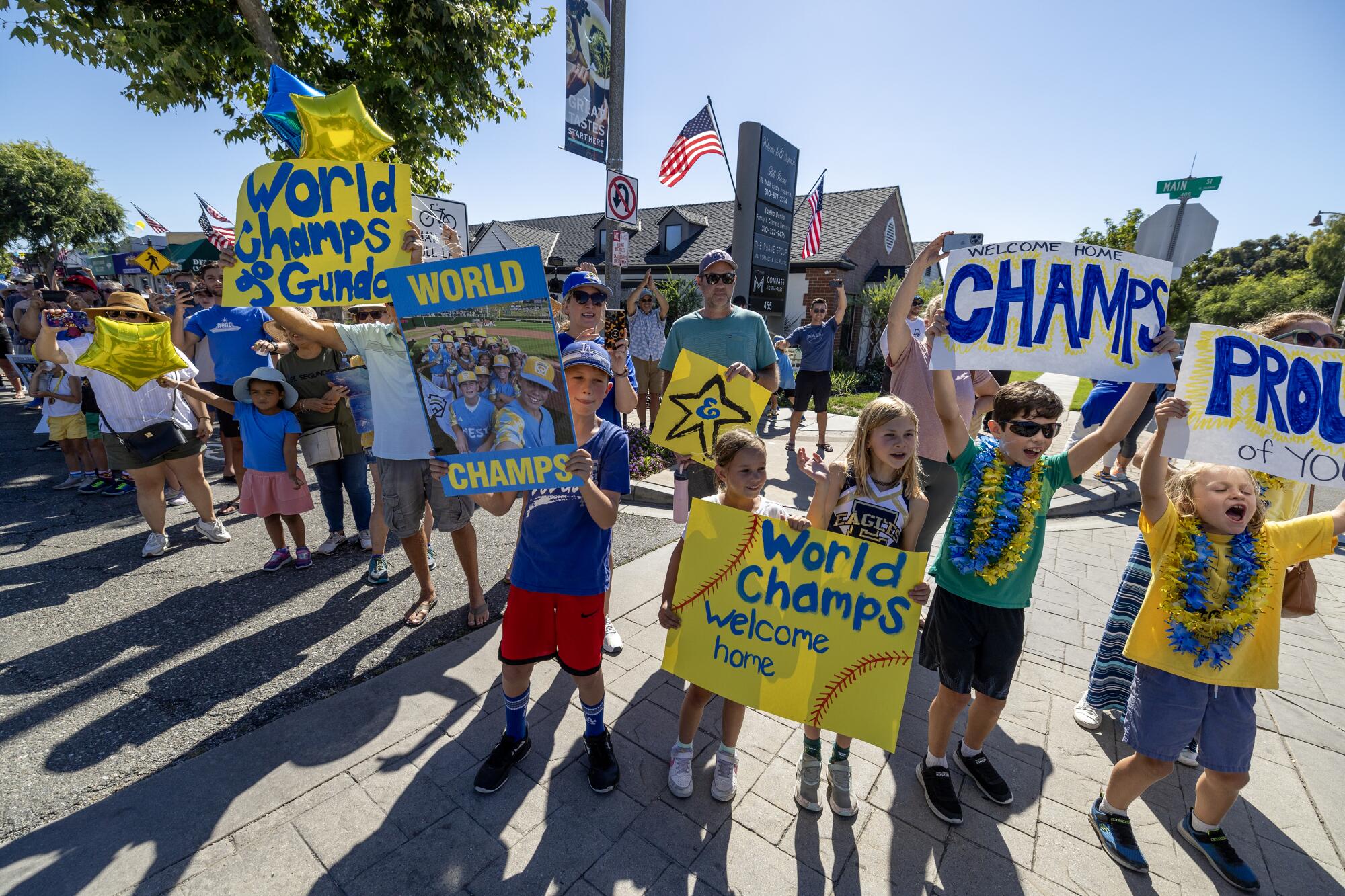 Jubelnde Erwachsene und Kinder halten Schilder mit der Aufschrift „ "Champs" Und "Stolz auf dich."
