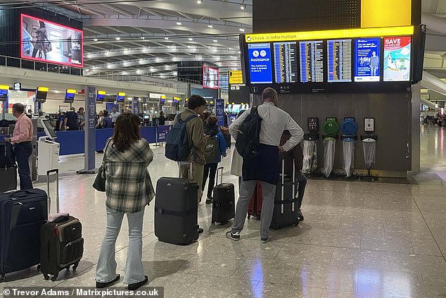 Passengers check the flight screens at Heathrow Airport this morning