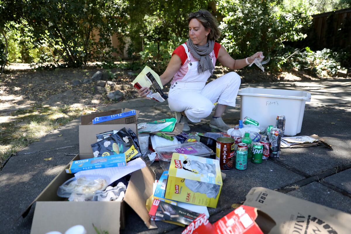 Susanne Rust geht in die Hocke, um den Müll ihrer Familie auf dem Boden zu sortieren 