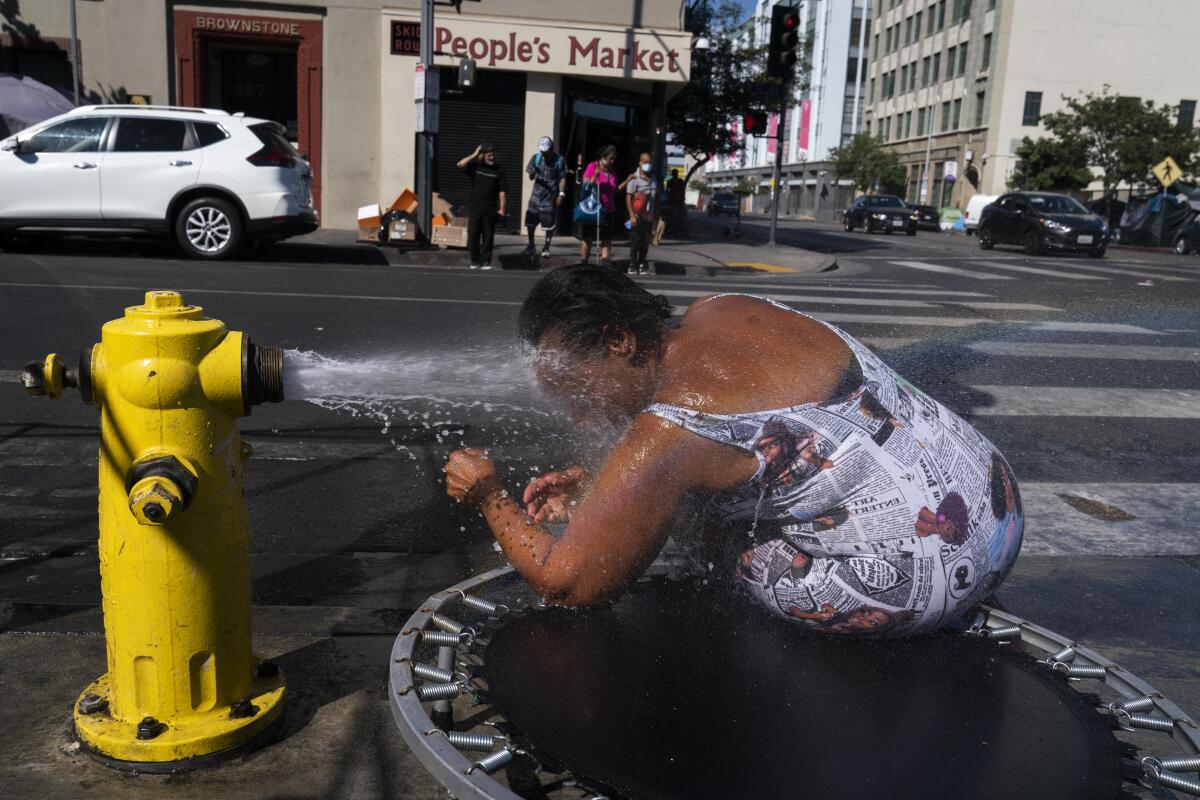 Eine Frau lehnt sich in den Wasserstrahl eines Hydranten