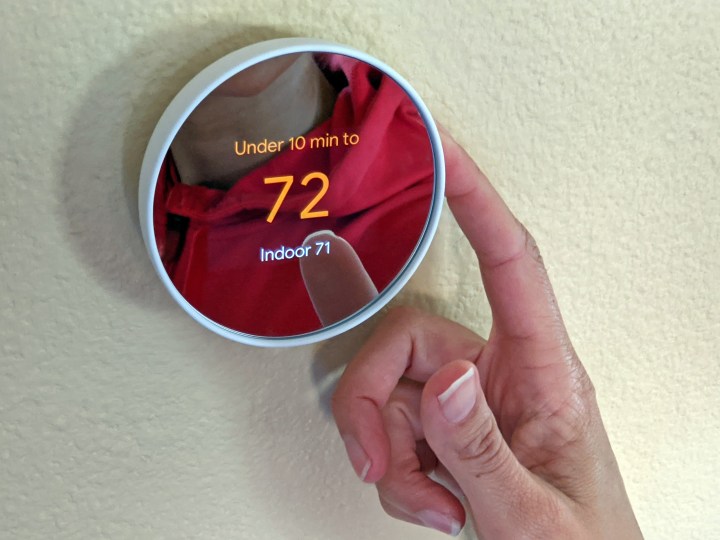 Eine Person, die den Google Nest-Thermostat bedient.