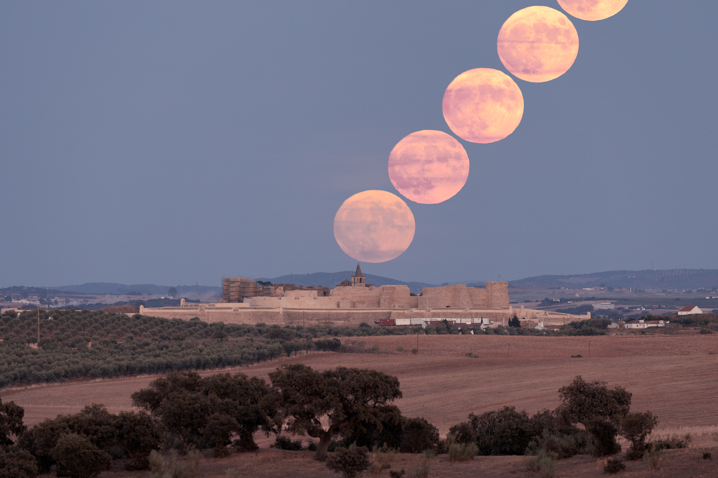 Eine Serie von fünf im Zeitraffer aufgenommenen superblauen Mondbildern scheint von einer alten Festung unten in den Himmel aufzusteigen.