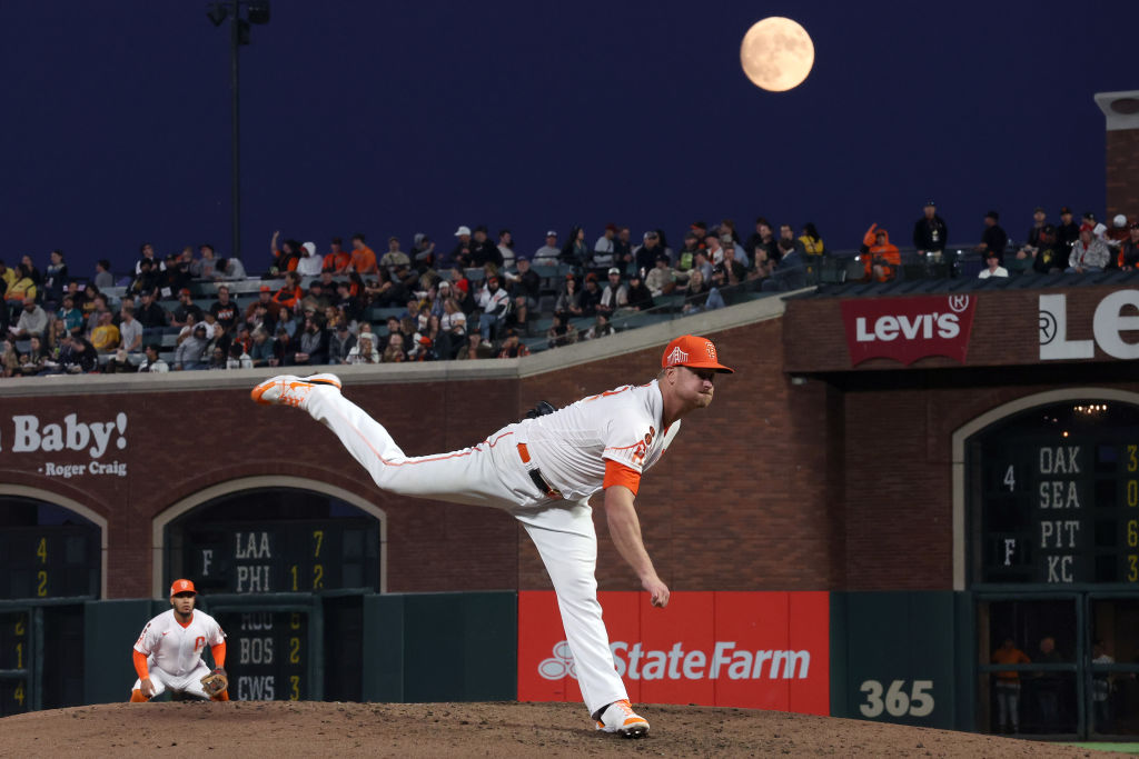 Superblauer Mond, der über einem Baseballspiel scheint, bei dem ein Spieler nach vorne springt.