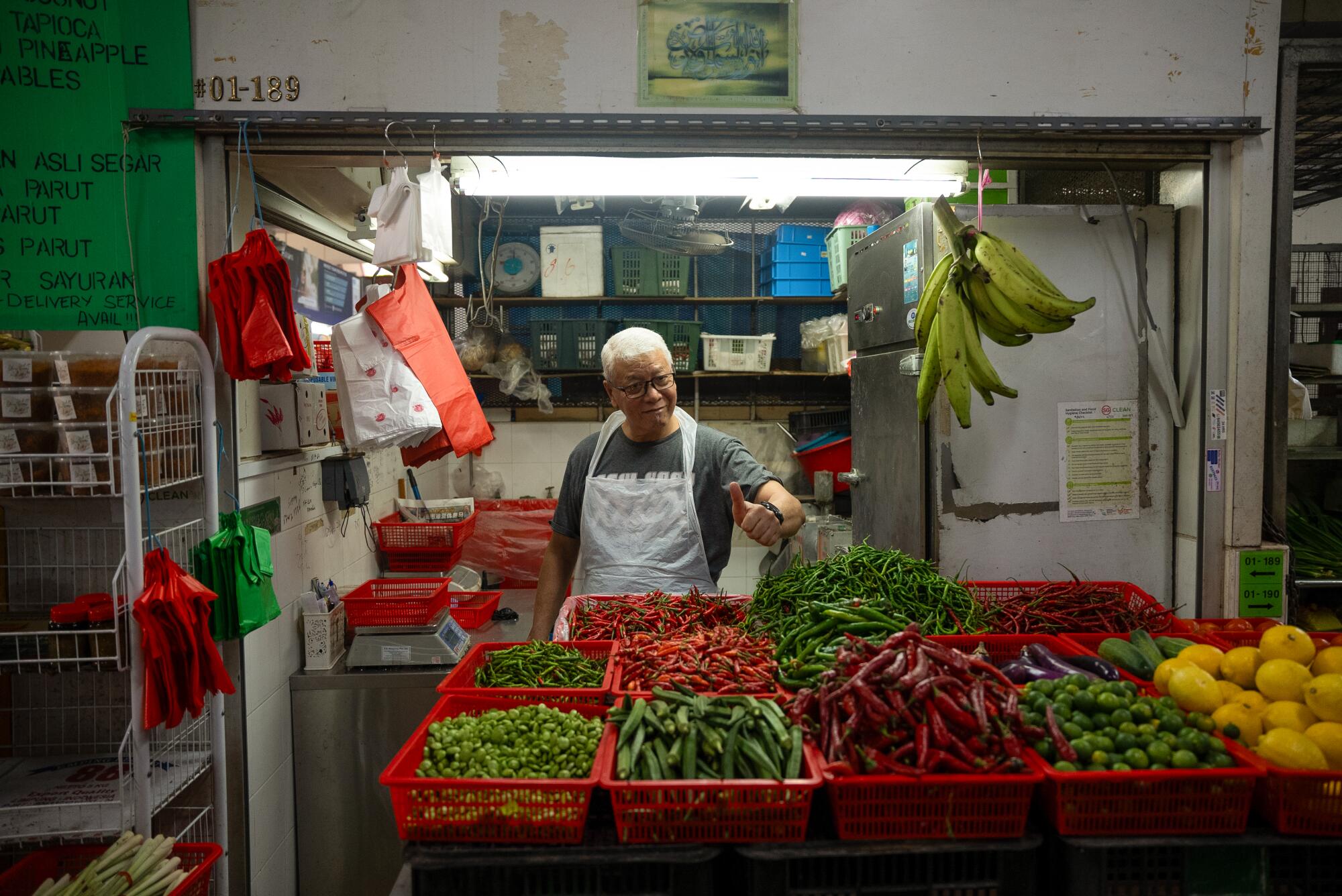 Ein Verkäufer lobt frische Chilis, Bohnen, Okraschoten, Auberginen und Zitrusfrüchte, die auf dem Geylang Serai-Markt verkauft werden.