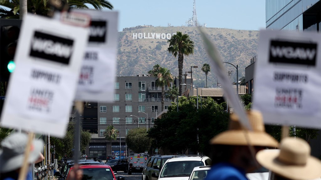 Menschen tragen WGA-Schilder, während streikende Mitarbeiter des W Hollywood Hotels von Unite Here Local 11 vor den Netflix-Büros in Los Angeles, Kalifornien, marschieren, um sich der Streiklinie von SAG-AFTRA und Writers Guild of America anzuschließen.