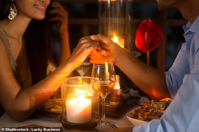 Ein Paar hält bei Kerzenschein bei einem romantischen Abendessen die Hände zusammen