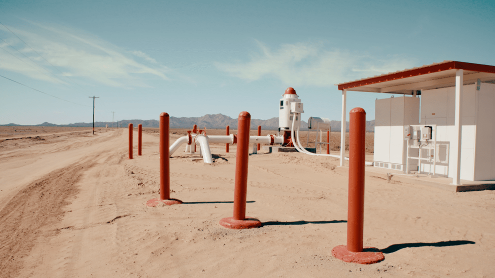 Eine neue Grundwasserpumpe, rot und weiß, mitten in einem Wüstengebiet.