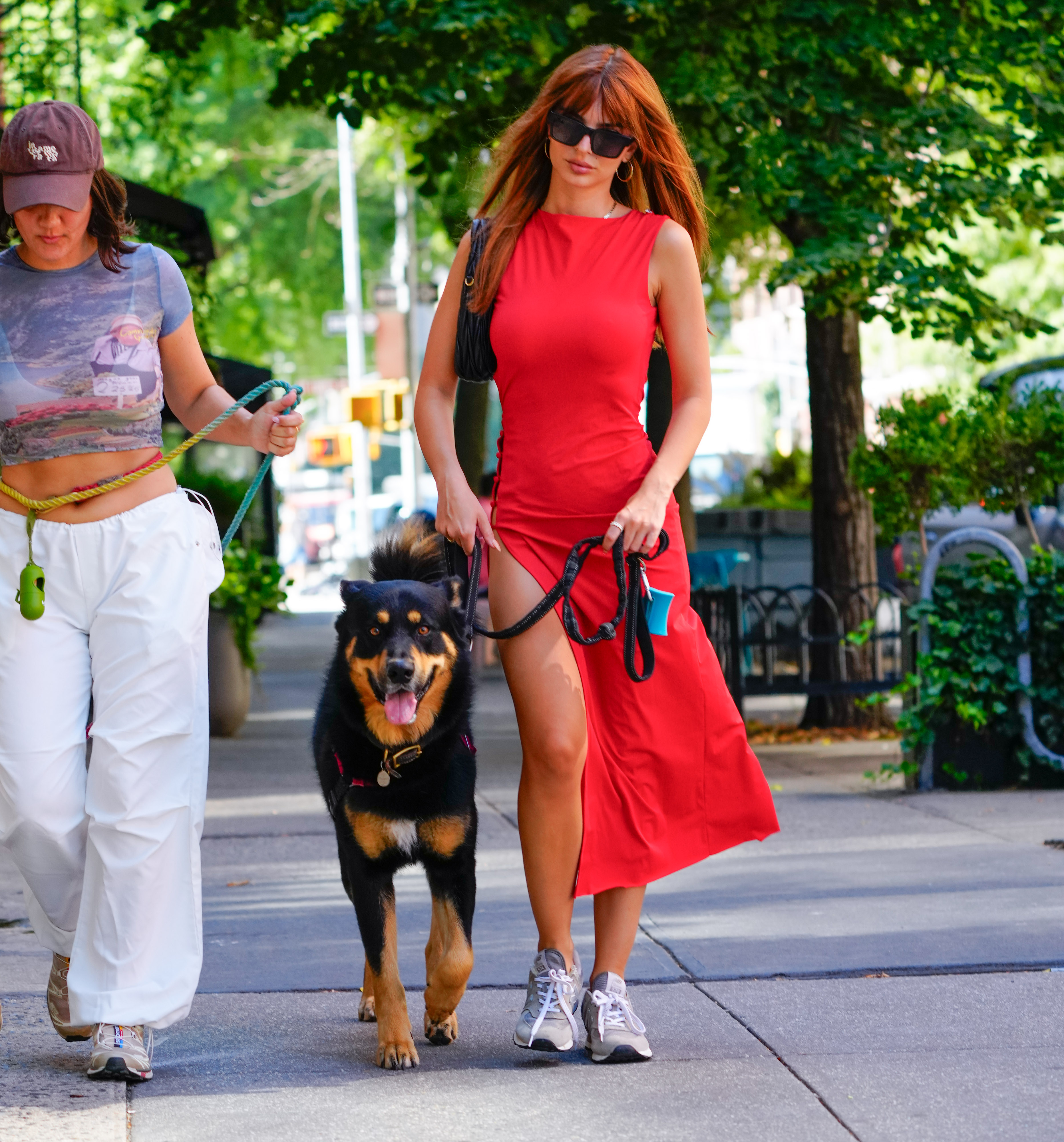 Emily Ratajkowski trägt ein hochgeschlitztes rotes Kleid und geht mit ihrem Hund spazieren