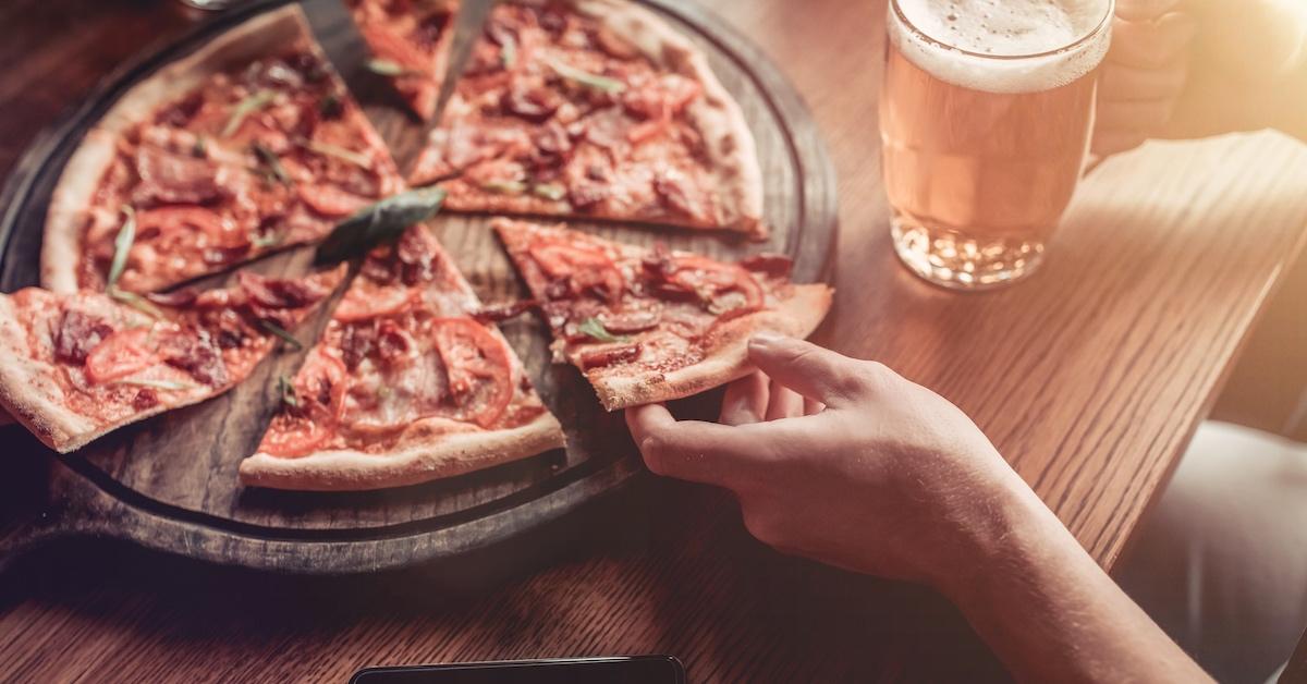 Eine Person, die Pizza und ein Bier genießt