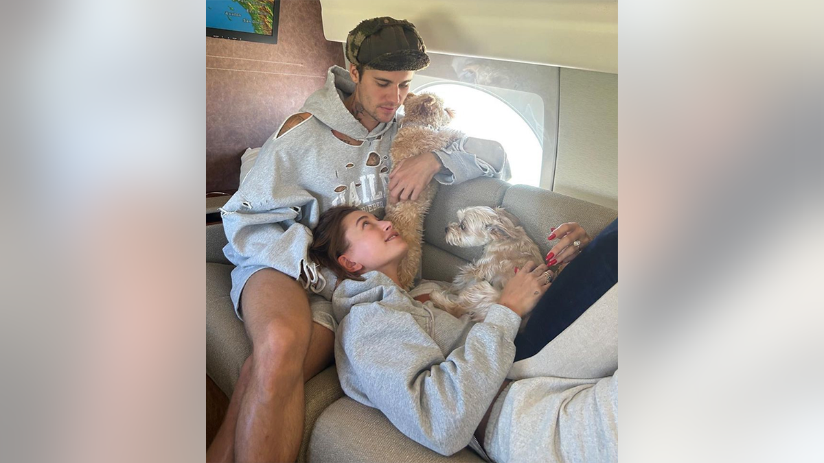 Justin Bieber schaut auf Hailey Bieber herab, die ein Sweatshirt trägt, auf dem ihr Name steht, und auf ihre beiden Hunde in einem Privatjet