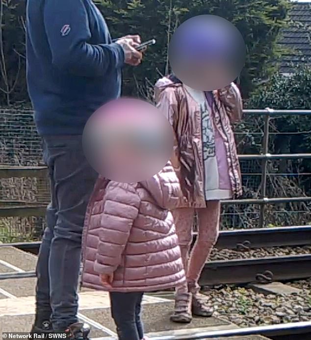 Ein zweifacher Vater, der seinen Töchtern erlaubte, auf einem Bahnübergang zu spielen, gehört zu denen, die von den Bahnchefs beschämt werden, die auf die Gefahren der Gleise hinweisen, wie CCTV-Aufnahmen zeigen
