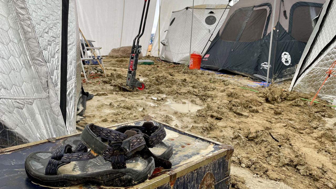 Ein Paar Teva-Sandalen liegen auf einer Truhe mitten in Zelten, nachdem heftiger Regen das Burning-Man-Festivalgelände in eine Schlammgrube verwandelt hat. 