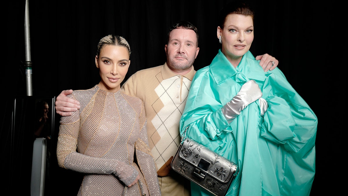 Kim Kardashian posiert in einem Overall neben Kim Jones in Schweiß, die bei der Fendi Spring 2023-Show neben Linda Evangelista in einem türkisfarbenen Mantel posiert