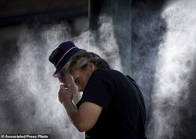 A man cools off at a temporary misting station deployed by the city in the Downtown Eastside due to a heat wave, in Vancouver, British Columbia, August 16, 2023