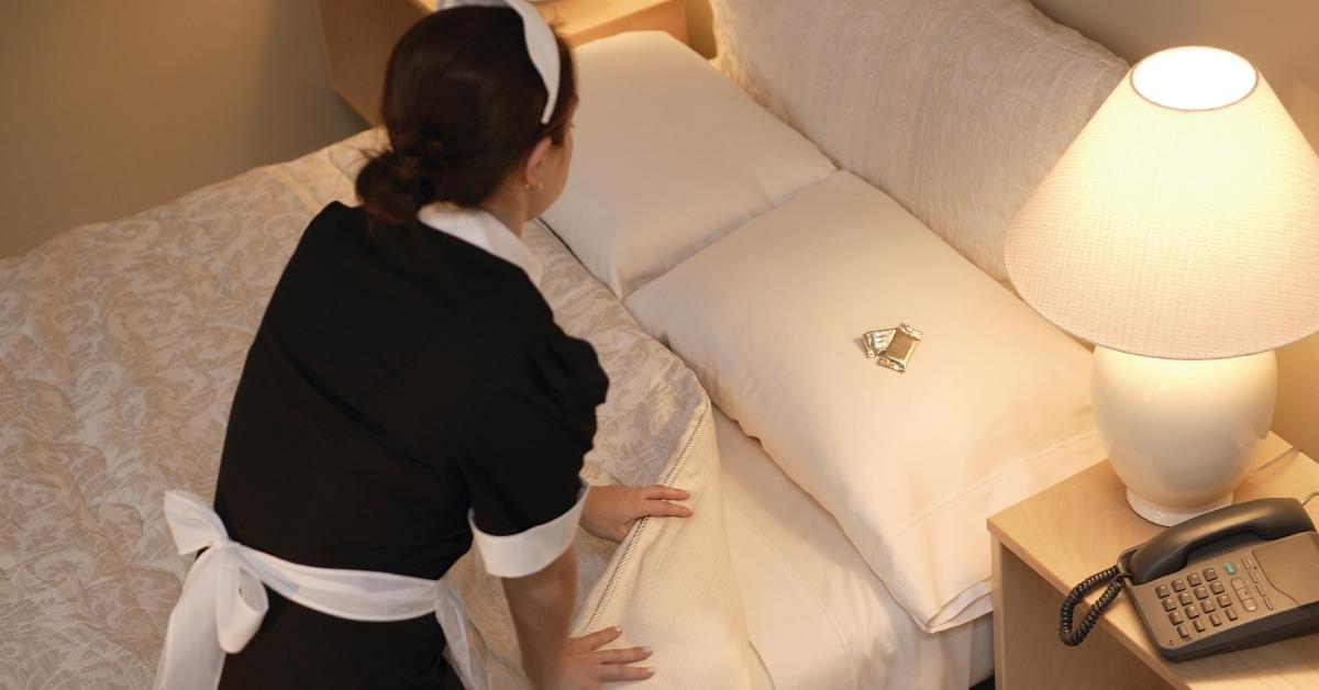 Dienstmädchen macht Bett und lässt Pralinen auf dem Kissen liegen