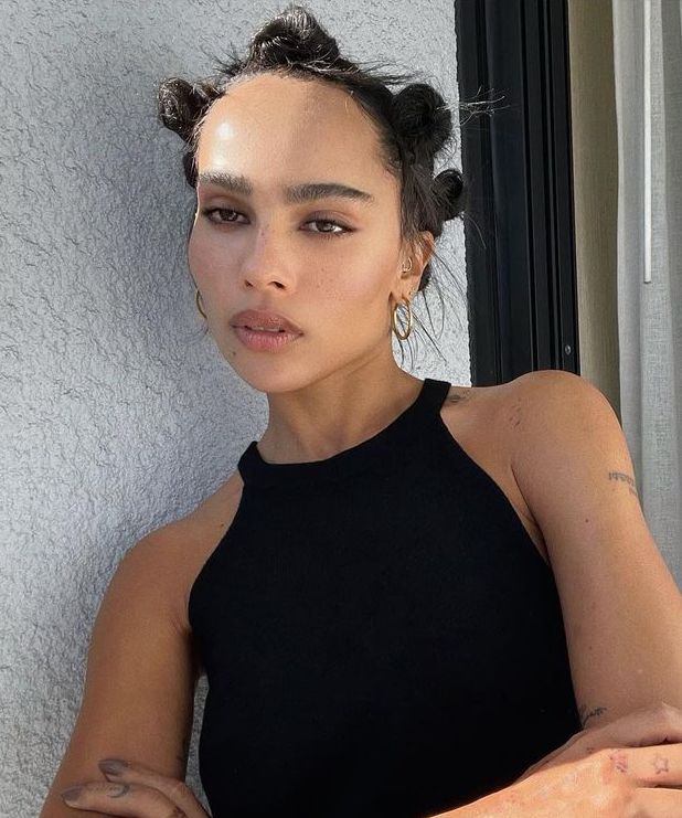 Zoe Kravitz in a black halter top with bantu knots and bushy brows '70s makeup trend