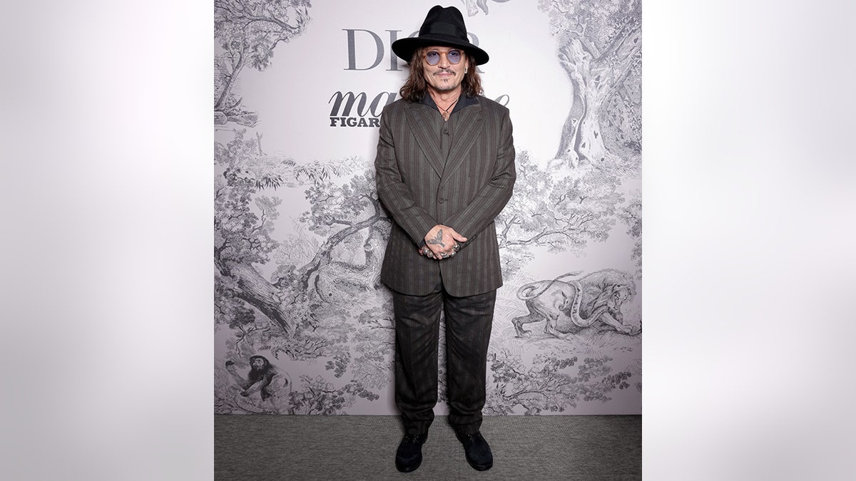 Johnny Depp in einem grau gestreiften Anzug, Hose und Hut bei einer Veranstaltung mit Dior